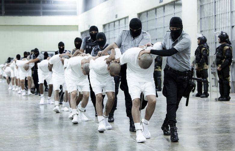 In this photo provided by El Salvador’s presidential press guards, prison guards transfer deportees from the U.S., alleged to be Venezuelan gang members, to the Terrorism Confinement Center in Tecoluca, El Salvador, Sunday, March 16, 2025. (El Salvador presidential press office via AP) MXEV101 MXEV101