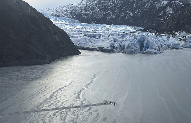 This photo provided by the Alaska National Guard shows an airplane partially submerged into the ice of Tustumena Lake at the toe of a glacier on Monday, March 24, 2025, near Soldotna, Alaska. (Alaska National Guard via AP) AKK504 AKK504