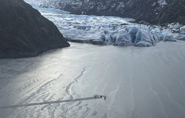 This photo provided by the Alaska National Guard shows an airplane partially submerged into the ice of Tustumena Lake at the toe of a glacier on Monday, March 24, 2025, near Soldotna, Alaska. (Alaska National Guard via AP) AKK504 AKK504