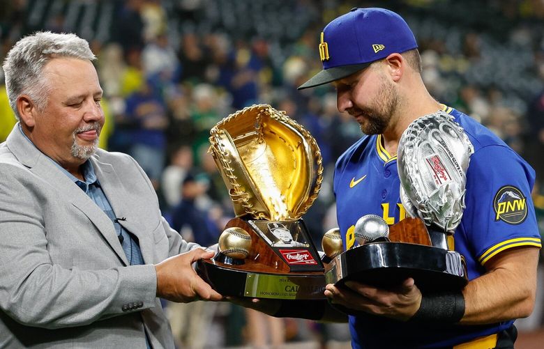 Cal Raleigh’s father, Todd, helps him out with honors won for last season’s play during pregame ceremonies Friday.  The Athletics played the Seattle Mariners in Major League Baseball Friday, March 28, 2025 at T-Mobile Park, Seattle, WA. 229557