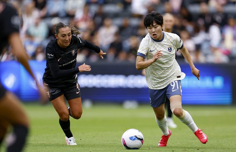 Reign midfielder Ji So-Yun brings the ball up field against Angel City FC on Sunday in Los Angeles.