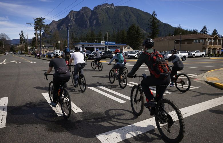The group takes off on bikes as Mount Si rises in the background during another leg of the “unofficial” Seattle Heptathlon, Tuesday, March 25, 2025, in North Bend.