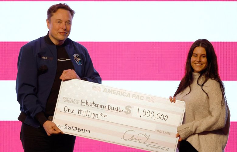 Elon Musk presents a check for $1 million dollars during a town hall Sunday, March 30, 2025, in Green Bay, Wis. (AP Photo/Jeffrey Phelps) WIJP170 WIJP170