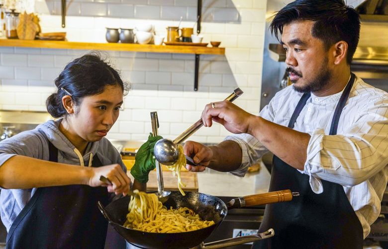 Ronnette Sanchez, left, and chef Aaron Verzosa prepare miki noodles for a dish at Archipelago restaurant, April 7, 2023, in the Hillman City neighborhood of Seattle.  223419