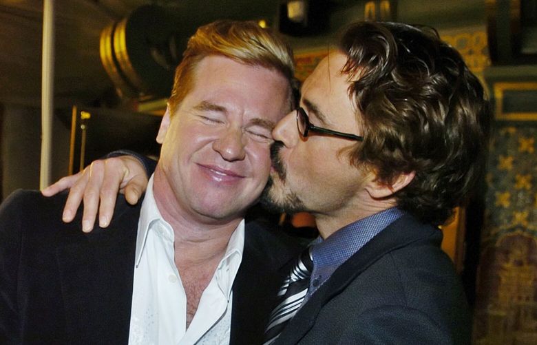 FILE – Val Kilmer, left, gets a kiss from fellow “Kiss Kiss Bang Bang” cast member Robert Downey Jr. at the West Coast premiere of the film in Los Angeles on Oct. 18, 2005. (AP Photo/Chris Pizzello, File) NYET303 NYET303