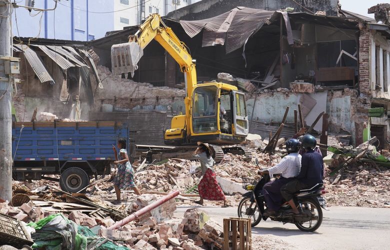 Local residents ride motorbikes while rescuers clean debris from damaged buildings in the aftermath of Friday’s earthquake in Naypyitaw, Myanmar, Wednesday, April 2, 2025. (AP Photo) XAS105 XAS105