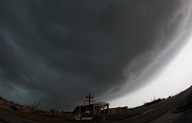 FILE- A cross stands atop a church that was severely damaged by a tornado in Joplin, Mo., as a severe storm passes overhead Monday, May 23, 2011.  (AP Photo/Charlie Riedel, File) NY906 NY906
