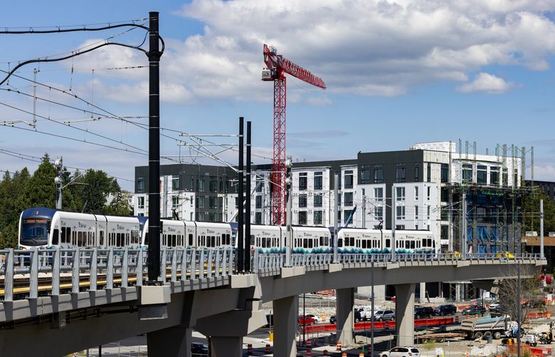 A light rail train is tested at Lynnwood City Center Station near an apartment building under construction, one of several in the works, Wednesday, July 24, 2024, in Lynnwood.