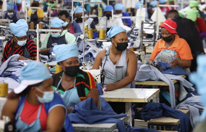 FILE – Matumelo Manosa, center, works in a garment factory in Maseru, Lesotho, Thursday, Feb. 24, 2022. (AP Photo/Neo Ntsoma, file ) LSO103 LSO103