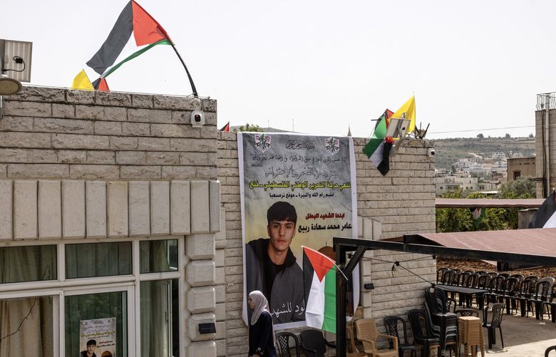 A woman walks past a giant poster showing Palestinian American Amer Rabee, 14, who was killed on Sunday. MUST CREDIT: Heidi Levine/For The Washington Post