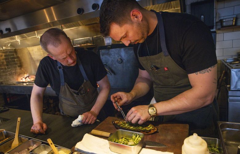 Cook Aaron Wopschall, left, bserve as restaurant owner and chef Berk Güldal prepares a dish at Hamdi in Seattle on Friday, April 11, 2025.