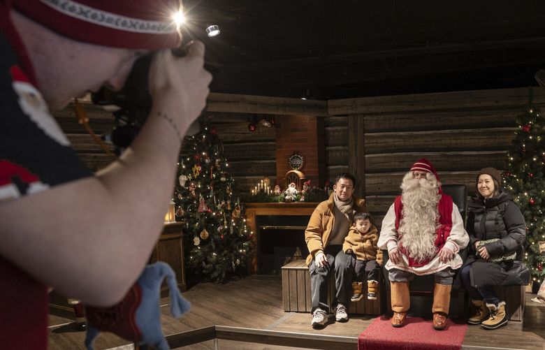 Tourists have their picture taken with one of the Santas at Santa Claus Village outside Rovaniemi, Finland, Feb. 23, 2025. A tourist season that stretches from October to March has been anything but jolly for some residents of the “Official Hometown of Santa Claus.” (Jim Huylebroek/The New York Times) XNYT0532 XNYT0532
