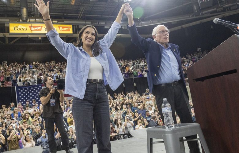 Rep. Alexandra Ocasio-Cortez, D-N.Y., holds hands with Bernie Sanders, I-Vt., during a “Fighting Oligarchy” event at the Ford Idaho Center in Nampa, Idaho, Monday, April 14, 2025. (AP Photo/Kyle Green) IDKG111 IDKG111