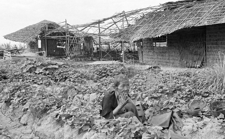 A Cambodian woman prayed for peace in a ditch in the family vegetable garden during a Khmer Rouge attack on Phnom Penh on Feb. 12, 1974. Her home, background, was destroyed in the attack. (The Associated Press)