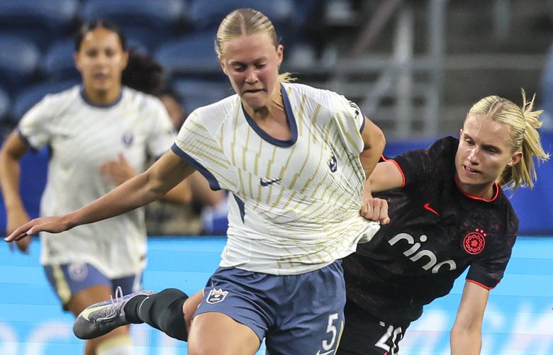 Portland Thorns FC defender Kaitlyn Torpey fouls and draws a yellow card with Seattle Reign forward Maddie Dahlien controlling the ball, Friday, April 18, 2025, in Seattle. The Reign lead 1-0 at the half.