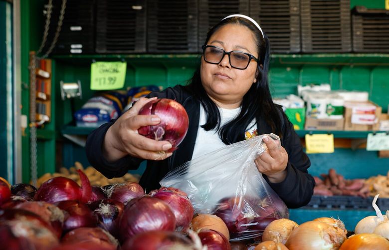 Claudibet Garcia, from Othello, shops for red onions at MacPherson’s Fruit & Produce on Beacon Hill in Seattle on Friday, April 11, 2025. She says she shops here alot because of the fresh produce.