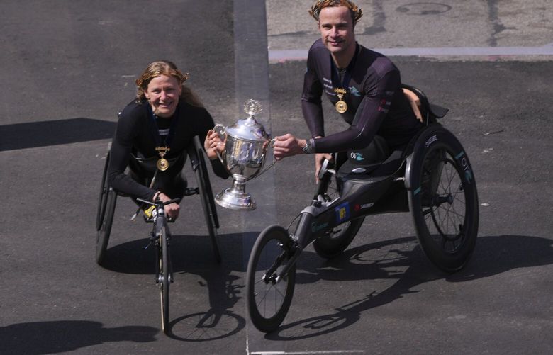 Marcel Hug, of Switzerland, right, and Susannah Scaroni, of the United States, hold up the winner’s trophy after winning the men’s and women’s wheelchair divisions during the Boston Marathon, Monday, April 21, 2025, in Boston. (AP Photo/Charles Krupa) MACK105 MACK105