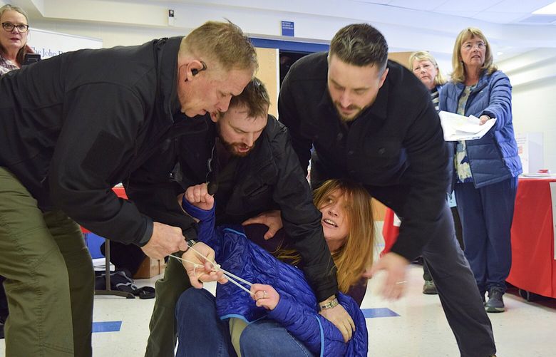 FILE – Employees of a security firm, LEAR Asset Management, drag Post Falls resident Teresa Borrenpohl out of a town hall meeting on Saturday, Feb. 22, 2025, in Post Falls, Idaho. (Hailey Hill/Coeur D’Alene Press via AP, File) IDCOE101 IDCOE101