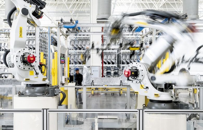 Robots and a worker at a factory of the electric carmaker Zeekr in Ningbo, China, March 31, 2025. Factories in cities all over China, including Zeekr’s facility in Ningbo, are being upgraded with robots and automation. (Qilai Shen/The New York Times)