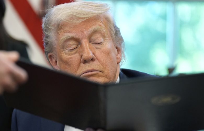 President Donald Trump is handed an executive order to sign by White House staff secretary Will Scharf in the Oval Office of the White House, Wednesday, April 23, 2025, in Washington. (AP Photo/Alex Brandon) DCJE347 DCJE347