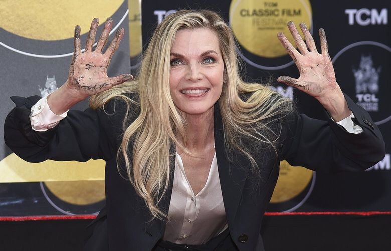Michelle Pfeiffer shows off wet cement on her hands during a hand and footprint ceremony in her honor on Friday, April 25, 2025, at the TCL Chinese Theatre in Los Angeles.