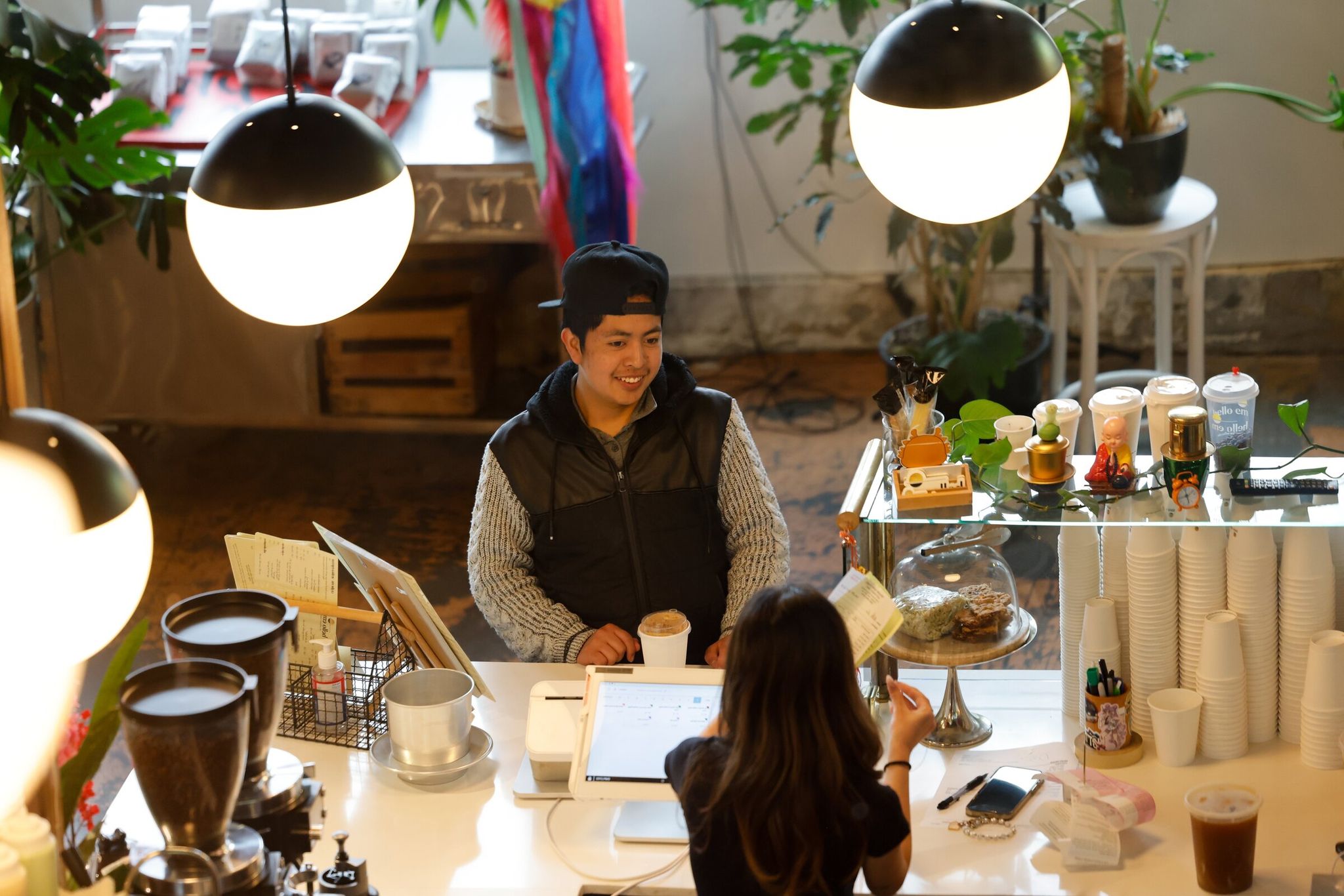 Марвин Мартин покупает напиток у Куана Вуонга, бариста, в кафе Hello Em Viet Coffee & Roastery, расположенном в здании Little Saigon Creative, 25 апреля 2025 года в Сиэтле. (Карен Дюси / The Seattle Times)