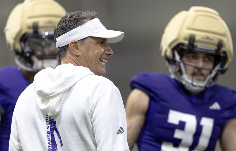 Washington head coach Jedd Fisch laughs with players during the team’s first spring practice on Tuesday, April 1, 2025, in Seattle.