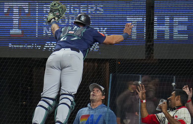 Seattle Mariners catcher Cal Raleigh makes a catch in foul territory for an out off the bat of Texas Rangers’ Wyatt Langford during the first inning of a baseball game Friday, May 2, 2025, in Arlington, Texas. (AP Photo/Julio Cortez) TXJC109 TXJC109