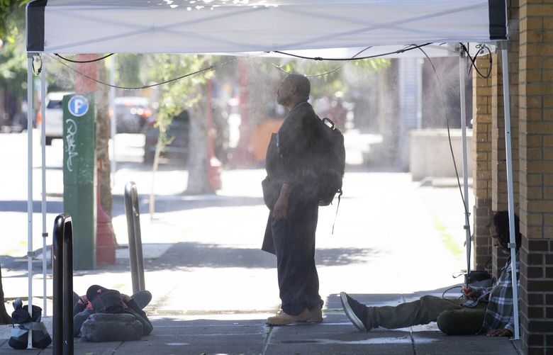 People use a misting tent outside of Blanchet House in downtown Portland, Ore., as a heat wave continues Monday, July 8, 2024. (Dave Killen/The Oregonian via AP)