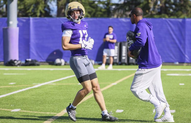 Washington Huskies wide receiver Audric Harris (13), left, trains with coach Kevin Cummings, right, on the practice field at Husky Stadium in Seattle  on Thursday, April 17, 2025.