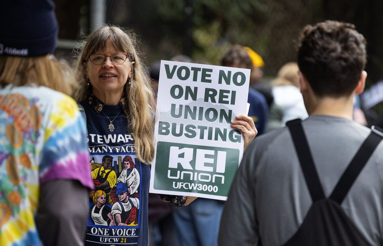 Britt Leggett, facing camera, a union steward with UFCW 3000 speaks with people passing a rally of REI workers and members during the launch of a campaign urging members to reject “corporate candidates” in the upcoming REI board of directors election, Monday, March 3, 2025, outside the flagship store in Seattle.