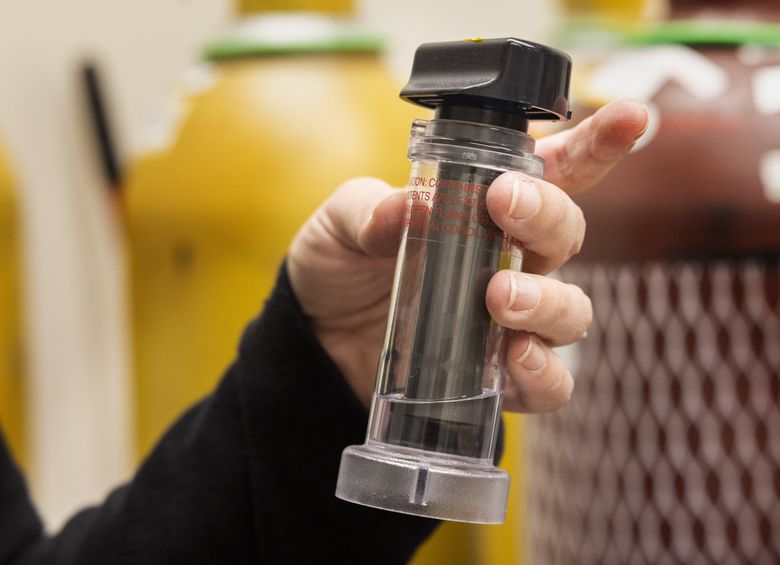 Elena Austin, a professor of environmental health at UW, holds an air quality instrument, part of a condensation particle counter, in her air quality lab Friday. (Ellen M. Banner / The Seattle Times)