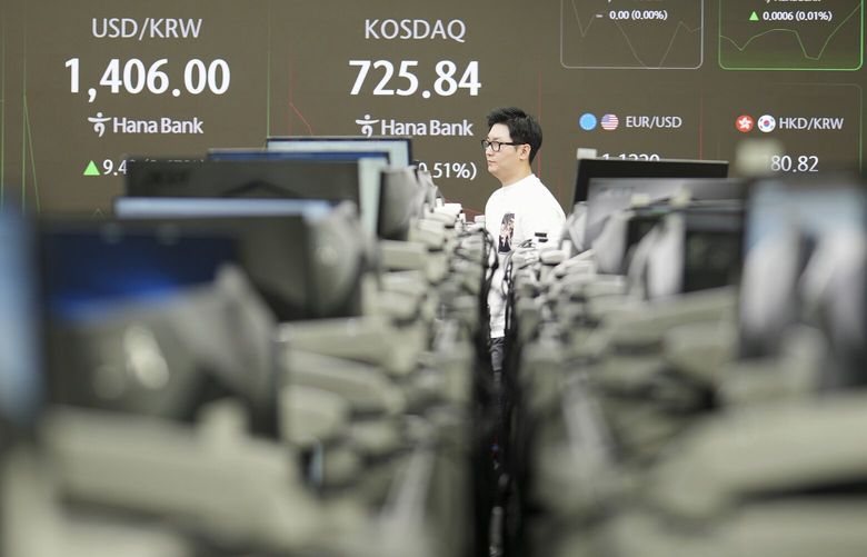 A dealer walks past near the screens showing the foreign exchange rate between U.S. dollar and South Korean won, left, and the Korean Securities Dealers Automated Quotations (KOSDAQ) are seen, at a dealing room of Hana Bank in Seoul, South Korea, Friday, May 9, 2025. (AP Photo/Lee Jin-man) LJM105 LJM105
