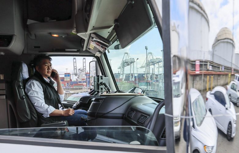 JK Choi, an independent truck owner-operator, makes a call from the cab of his truck on April 30, 2025. Choi has noticed a decrease in transportation demand in Seattle, Washington. (Kevin Clark / The Seattle Times)