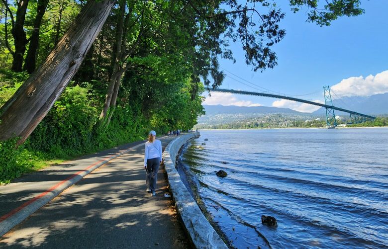 A person walks near a part of Stanley Park’s Vancouver Seawall in Vancouver.