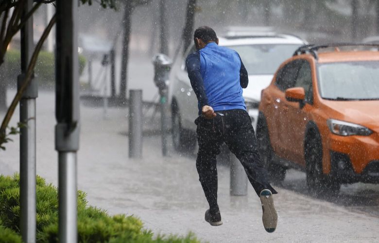 A man runs down the sidewalk along Commerce Street while heavy rain fall in downtown Dallas last month. (Elías Valverde II / The Dallas Morning News via The Associated Press)