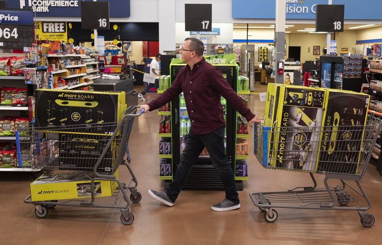 Juston Herbert pushes two carts full of Morf Boards, a popular kids toy, through a Walmart in Phoenix in 2019. (Dominic Valente/For The Washington Post)