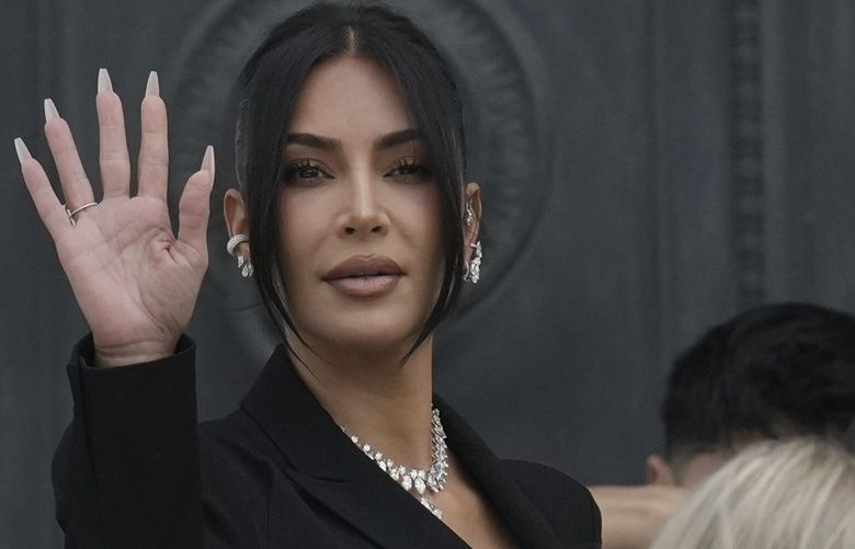 Kim Kardashian waves as she arrives to testify regarding a robbery of millions of dollars in jewels from her Paris hotel room in 2016, in Paris, Tuesday, May 13, 2025. (AP Photo/Aurelien Morissard) XVM146 XVM146