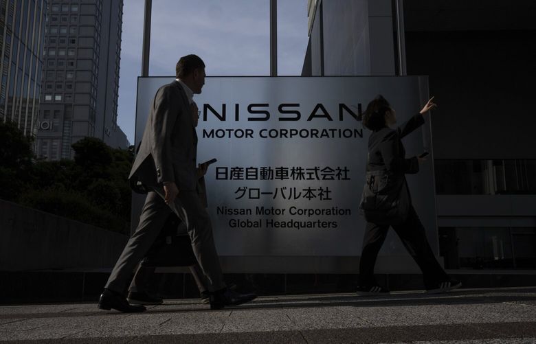 Visitors walk past Nissan signage at Nissan headquarters in Yokohama, Tuesday, May 13, 2025. (AP Photo/Louise Delmotte) XLD102 XLD102