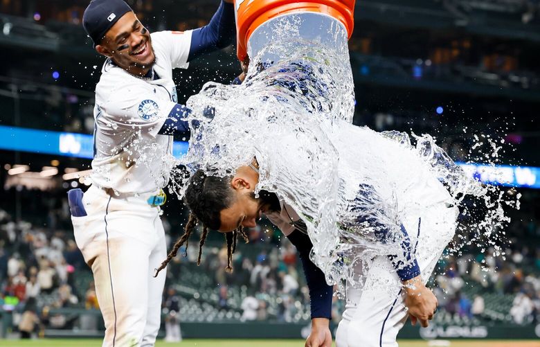 Seattle Mariners shortstop J.P. Crawford gets a ice water shower from teammate Julio Rodriguez after Crawford hit the walk-off RBI single in the eleventh inning Tuesday, May 13, 2025 in Seattle.