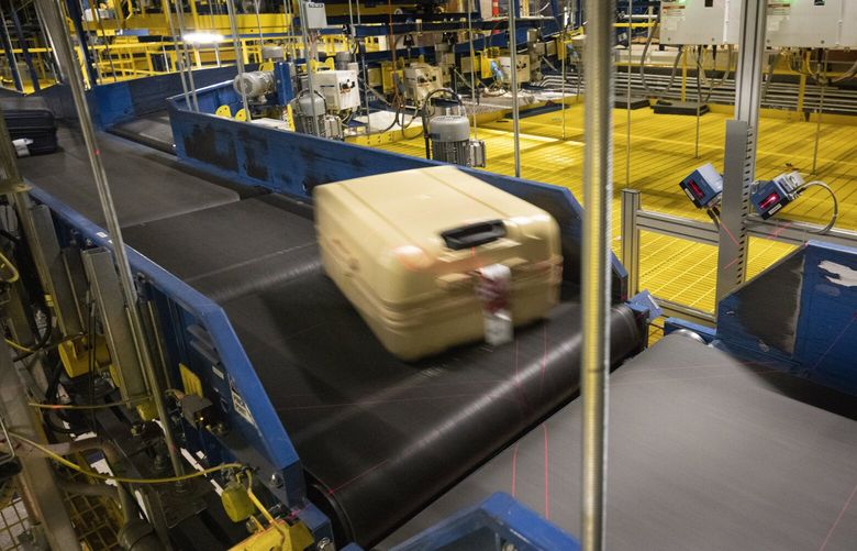 An automatic tag reader reads a baggage tag to make sure it gets on the right plane as it passes by on a conveyor belt at SEA Tuesday, March 28, 2023. There are ten miles of conveyor belts at the airport to handle all of the luggage.
This is for a “behind the scenes” at SEA, shot Monday, March 27 and Tuesday, March 28, 2023 for a Pacific magazine story. 223365