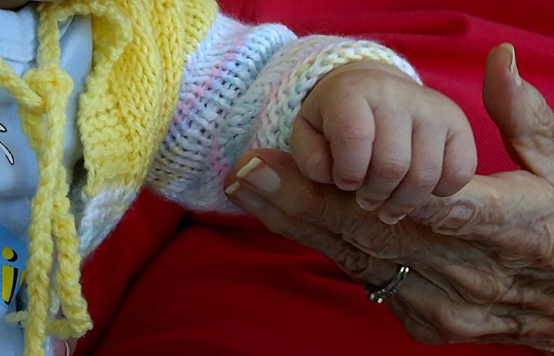 A Seattle resident, holds hands with a three-month-old baby in West Seattle on May 16, 2017. (Ellen M. Banner / The Seattle Times)