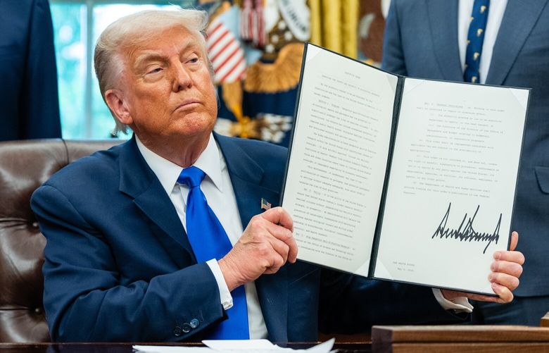 FILE – President Donald Trump is flanked by Jay Bhattacharya, left, the NIH director, and Health and Human Services Secretary Robert F. Kennedy Jr., as he holds up a signed executive order in the Oval Office of the White House in Washington, May 5, 2025. Trump will sign an executive order on Monday, May 12, aimed at lowering some drug prices in the United States by aligning them with what other wealthy countries pay, he said on Truth Social on Sunday evening. (Eric Lee/The New York Times) XNYT0647 XNYT0647