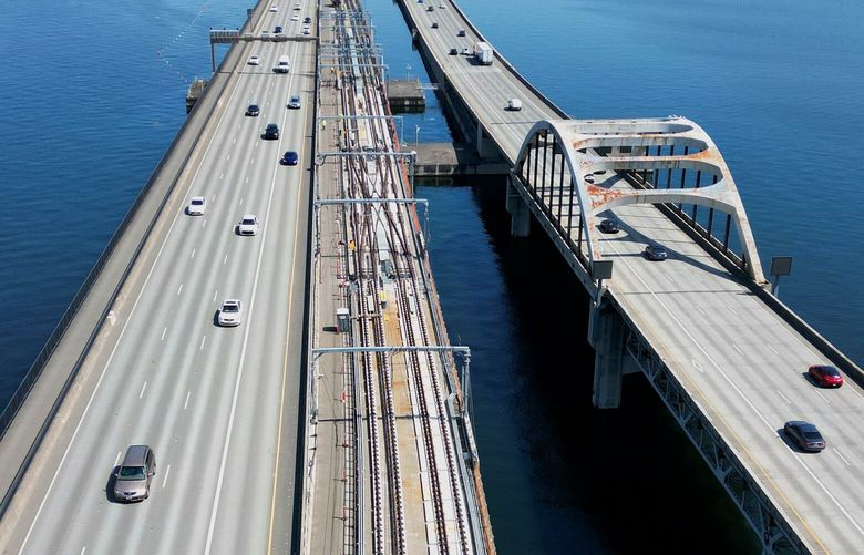 Aerial view of work being done on  Sound Transit Light Rail tracks (at center) going over the I-90 floating bridge, facing east towards Mercer Island (at top), Bellevue city skyline is at top left, shot Wednesday, April 23, 2025.  
 Sound Transit predicts that Line 2 from Seattle to Bellevue over the I-90 floating bridge will open later in 2025. 

 This is the part of the Line 2 East Link Extension part of Sound Transit’s Light Rail section that runs from Seattle’s International District to the Judkins Park station in Seattle, across the floating I-90 bridge to the Redmond Technology station in Redmond.  The East Link Extension currently includes ten stations —  International District station,  Judkins Park station, Mercer Island station,  South Bellevue station, East Main station, Bellevue Downtown station, Wilburton station, Spring District station, BelRed station, Overlake Village station and then the Redmond Technology station.  Two more stations in Redmond,  the SE Redmond Station and Downtown Station, will open in May of 2025. 229816 229816