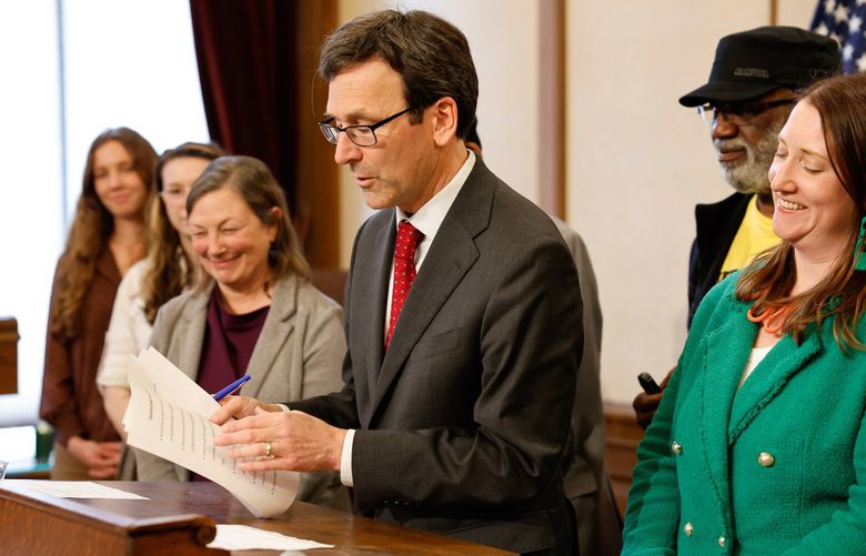 Sen. June Robinson (D-Everett), left, and Sen. Noel Frame (D-Seattle), right, and others lawmakers stand with Gov. Bob Ferguson as he signs the Engrossed Substitute Senate Bill No. 5167 in the Governor’s Conference Room at the Washington State Capitol in Olympia on May 20, 2025.