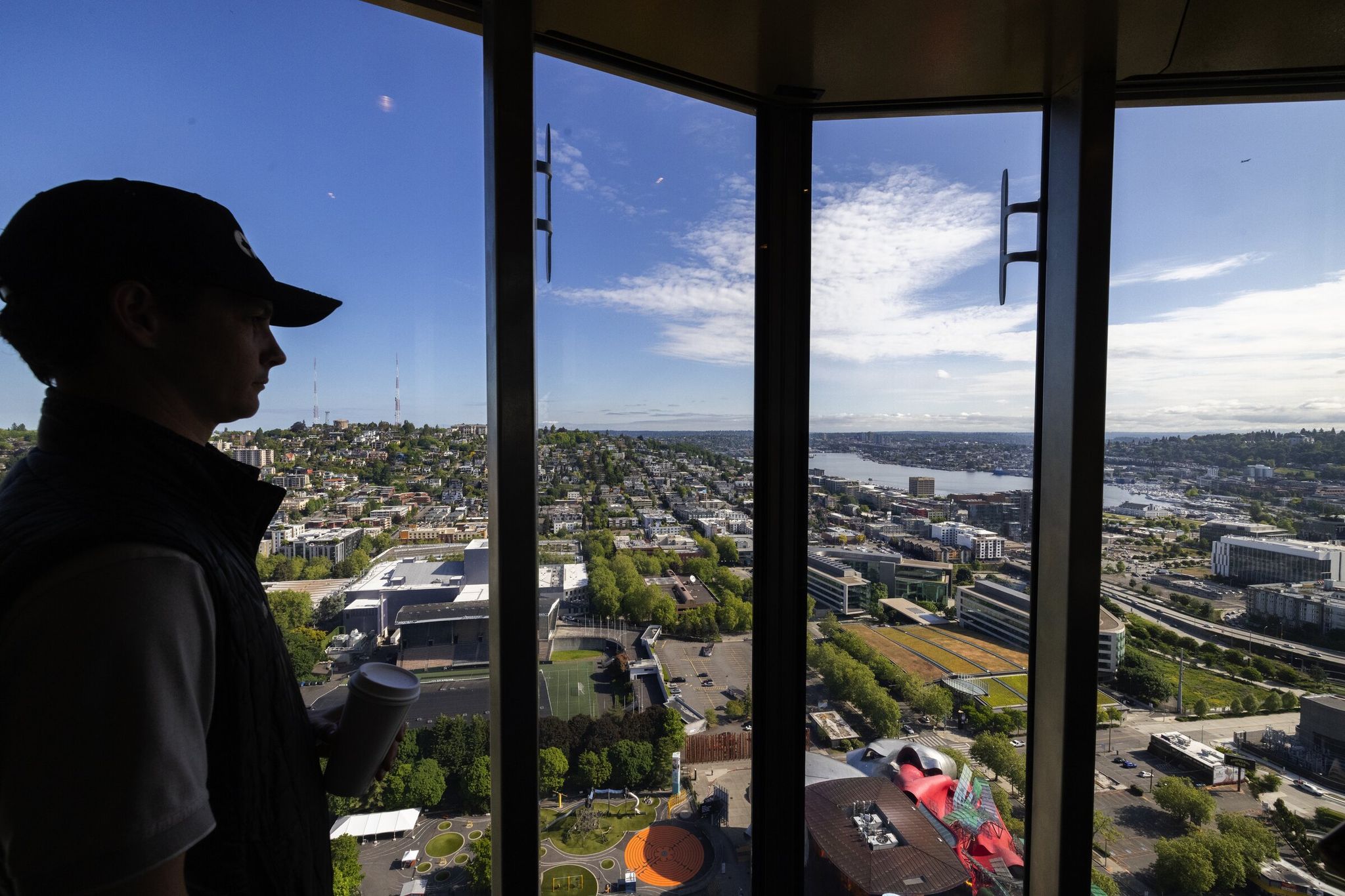 Грант Беррихилл, старший менеджер компании Otis Elevator и руководитель проекта на Space Needle, демонстрирует вид из нового полностью стеклянного двухэтажного открытого лифта на Space Needle в четверг, 22 мая 2025 года, в Сиэтле. Беррихилл курирует проект по преобразованию лифтов Needle в двухэтажные. (Кен Ламберт / The Seattle Times)