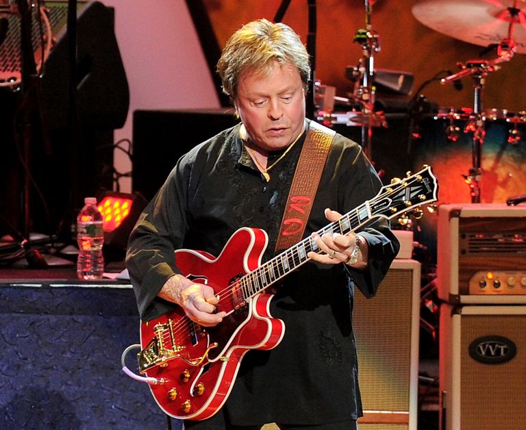 Rick Derringer performing on stage with his guitar.