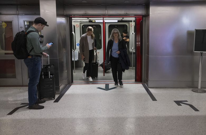 Arrows at train station stops at Seattle-Tacoma International Airport have been taped to the floor so passengers know to stand to the side to give others departing the train a clear path. (Ellen M. Banner / The Seattle Times)