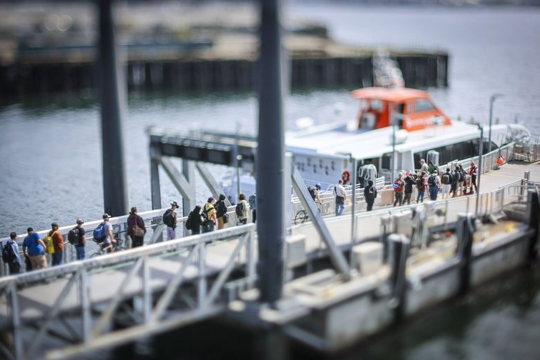 People walk aboard a passenger ferry at Seattle’s Pier 50. There are several ferry and water taxi options on the waterfront. (Kevin Clark / The Seattle Times)
