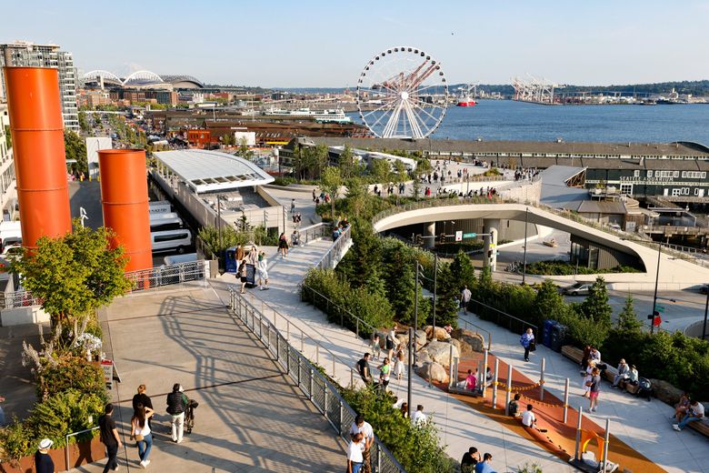 The view encompasses the natural and the industrial: stadiums, a ghostly Mount Rainier, cranes, a Ferris wheel, greenery, water. (Karen Ducey / The Seattle Times)